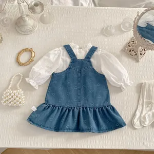 Detail of white ruffle collar shirt and blue denim dress with heart embroidery for girls