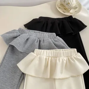 Dettaglio di pantaloni con volant per bambina in nero, grigio e beige in cotone
