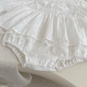 Detail of white cotton baby romper with lace ruffles and bottom snap button closure