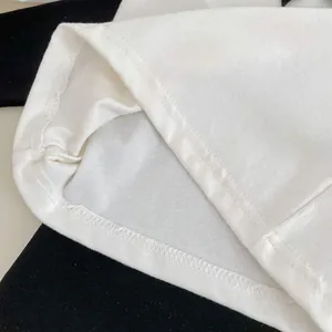 Dettaglio dell'orlo con doppia cucitura e trama in cotone sulla maglia bianca da bambina