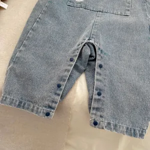 Dettaglio dei bottoni a pressione sul cavallo di una salopette in denim per neonati