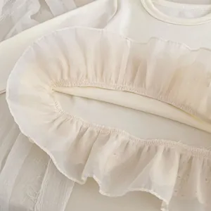 Detailed close-up of cream white cotton kids top featuring pleated tulle and fine stitching