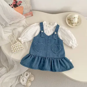 Detail view of toddler girl outfit with heart-pockets denim dress and ruffle shirt