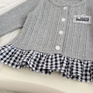 Detail van grijs gebreid vest met geruite ruches aan de zoom en kanten hartborduursel