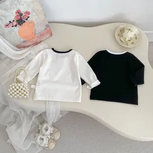 Dettaglio di t-shirt neonato a maniche lunghe con pizzo su un tavolo decorativo