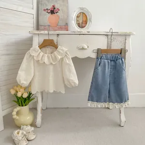 Dettaglio della camicia ricamata con volant e jeans con bordo in pizzo set