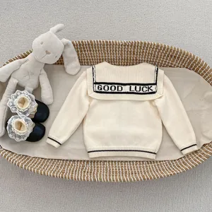 Detailed view of knitted cardigan back with GOOD LUCK lettering in a cozy nursery cradle