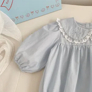 Detail of baby girl bodysuit with white lace doll collar and blue bow embroidery