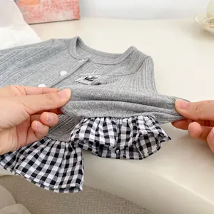 Detailopname van grijs gebreid babyvestje met elastische ribstof en geruite ruches aan de zoom