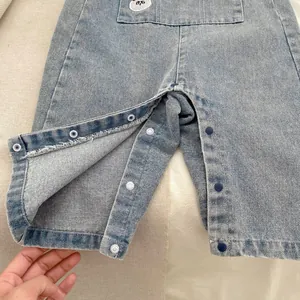 Dettaglio salopette di jeans con bottoni automatici sul cavallo per un facile cambio pannolino