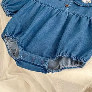 Detail of baby denim romper featuring cute cartoon embroidery and snap button closure