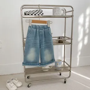 Detail view of light blue denim shorts with elastic waist and rolled-up cuffs on a cart