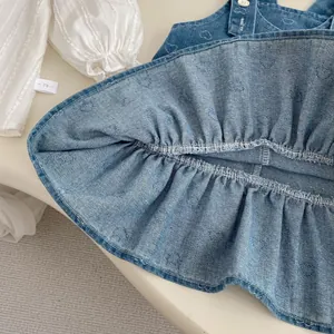 Detail of baby girl denim pinafore dress with heart pattern and textured long sleeve shirt
