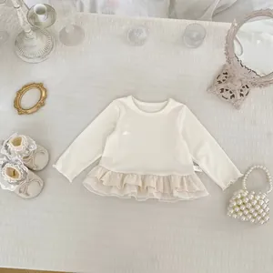 Detail of baby girl cream ruffle top with lace hem and size 73 tag on textured fabric