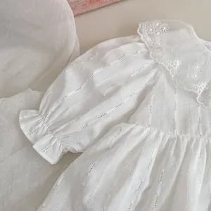 Detailed view of white baby dress featuring lace collar and textured hollow stripe fabric