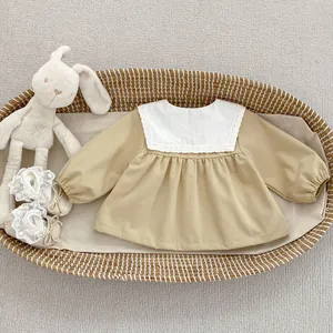 Detailed view of girls' khaki long-sleeve dress with white lace collar and soft baby shoes