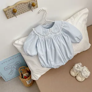 Close-up of baby romper with lace Peter Pan collar and embroidered bow detail