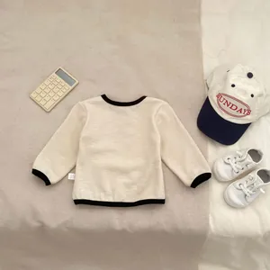 Detail of baby boy waffle knit long sleeve top with contrast trim and side label tag