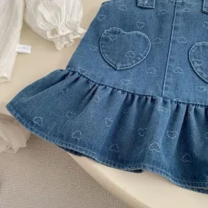 Detailed embroidery of white hearts and pockets on light blue denim overall dress