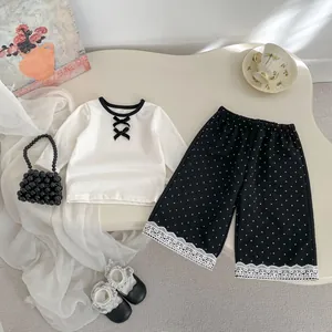 Dettaglio dei pantaloni a pois e del top con bordi in pizzo e fiocchi per bambine