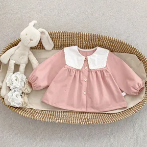 Detail of pink toddler shirt with lace collar and baby shoes in a woven basket