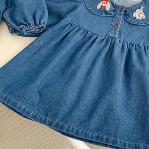 Detail of girls denim dress featuring cute cartoon animal embroidery on Peter Pan collar