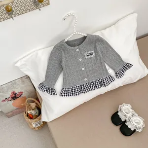 Detail van grijs gebreid vest met geruite zoom en schattige baby schoentjes