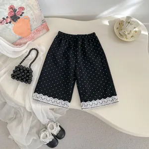 Dettaglio dei pantaloni neri a pois per bambina con bordo in pizzo bianco decorativo