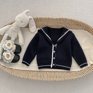 Detail of toddler navy knit cardigan with white lapel and buttons in a cozy setting
