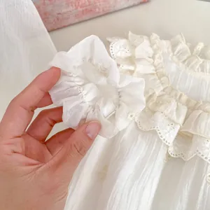 Detailaufnahme des weißen Baby-Stramplers mit feiner Spitze und weicher Baumwollstruktur