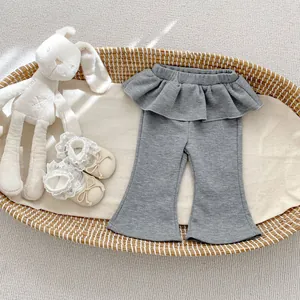 Dettaglio dei pantaloni a zampa grigi per neonata con balza in vita e decorazioni