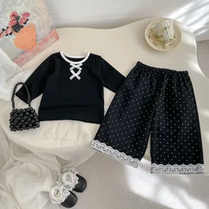 Dettaglio dei pantaloni a gamba larga a pois per bambine con bordo in pizzo floreale