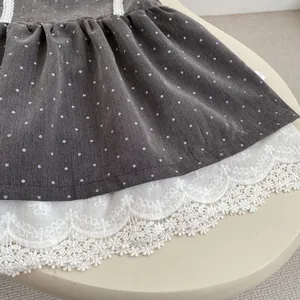 Detalle de vestido de algodón gris oscuro con lunares blancos y ribete de encaje bordado