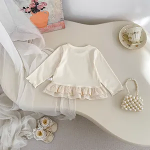 Detail of cream long sleeve cotton top for girls with layered lace hem and soft texture