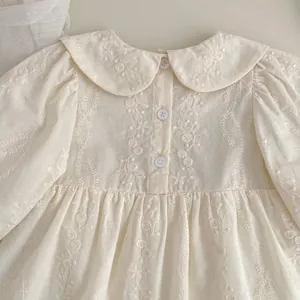 Dettaglio di pagliaccetto beige per neonata con ricami floreali e colletto Peter Pan retrò