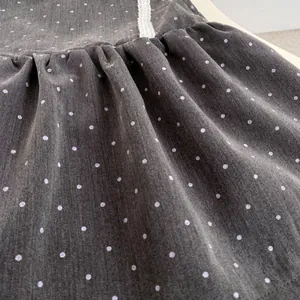 Detalle del vestido gris oscuro con lunares, ribete de encaje blanco y cintura fruncida