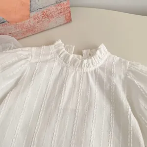 Detail of white long-sleeve girl's shirt with ruffled collar and striped jacquard fabric