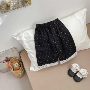 Dettaglio dei pantaloni per bambine a pois neri con delicato bordo in pizzo bianco sull'orlo