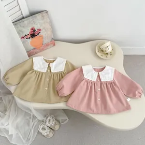 Detail of baby girl's cotton blouse with lace doll collar and front buttons