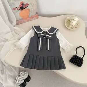 Detalle de conjunto escolar para niña con falda plisada y encaje en camisa blanca
