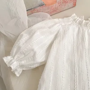 Detailed view of white long-sleeved shirt with puff sleeves and ruffled cuffs texture