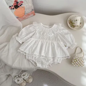 Detail of white infant lace romper with embroidered ruffles and vintage pearl styling