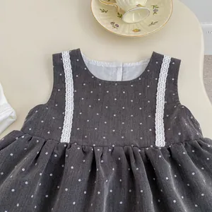 Detalle de vestido gris para niña con lunares blancos, encaje delicado y volantes finos