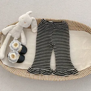 Detail of girls' black and white striped flare pants with elastic waist and ruffled hems