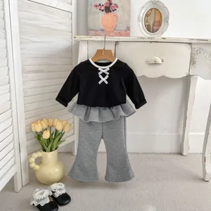 Dettaglio del set per bambina con top a fiocchi e pantaloni a pieghe su una gruccia