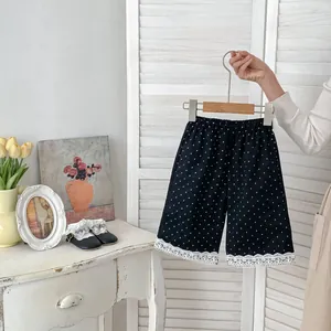 Dettaglio dei pantaloni neri a pois per bambina con delicato bordo in pizzo bianco fine