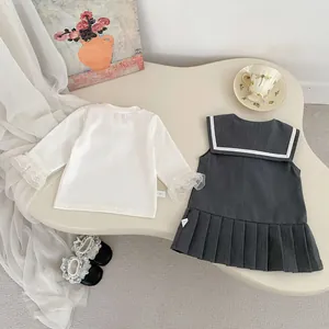 Detalle de conjunto de dos piezas estilo preppy para niña con puños de encaje y falda