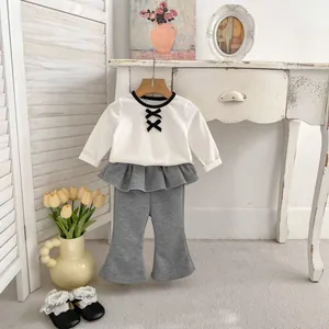 Dettaglio completo bimba con maglia a maniche lunghe e pantaloni a zampa grigi eleganti