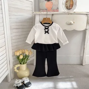 Dettaglio top bianco a maniche lunghe con fiocchi e pantaloni con volant da bimba