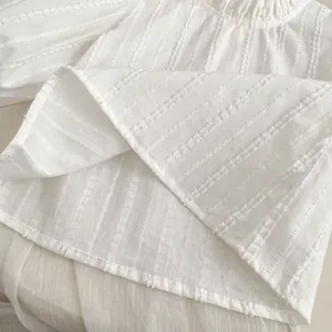 Detail of white cotton shirt showing textured stripe seersucker fabric and neat stitching